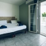 Chambre supérieure avec des portes-fenêtres ouvertes accédant à la terrasse, laissant entrer la lumière.
