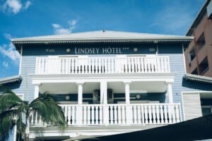 Vue de la façade blanche et bleue à étages du Lindsey Hôtel avec ses balcons en bois.