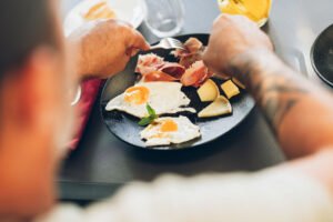 Vue rapprochée d'une assiette contenant des œufs au plat, du jambon cru et des tranches de fromage.