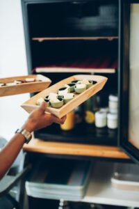 Une main présente un plateau en bois garni de beurre