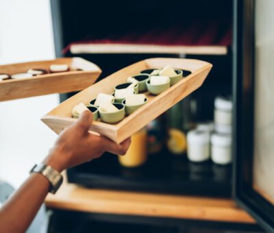 Une main présente un plateau en bois garni de beurre