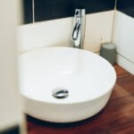 ue rapprochée d'une vasque blanche moderne posée sur un plan de toilette en bois, accompagnée d'un robinet chromé.