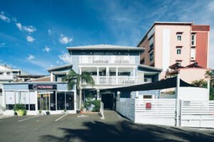 ue large de l'établissement Lindsey Hôtel sous un ciel bleu avec un palmier sur le côté.
