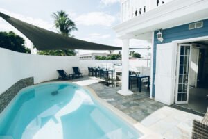 Espace détente extérieur combinant piscine, transats et tables de restaurant sous un parasol géant.