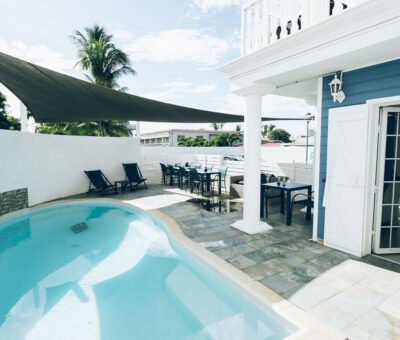 Espace détente extérieur combinant piscine, transats et tables de restaurant sous un parasol géant.