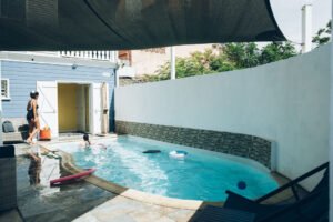 Bassin de piscine extérieure entouré de murs blancs avec une voile d'ombrage au-dessus