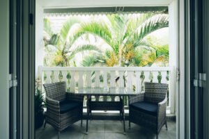 Terrasse extérieure bordée de plantes tropicales luxuriantes et de palmiers sous un ciel clair.